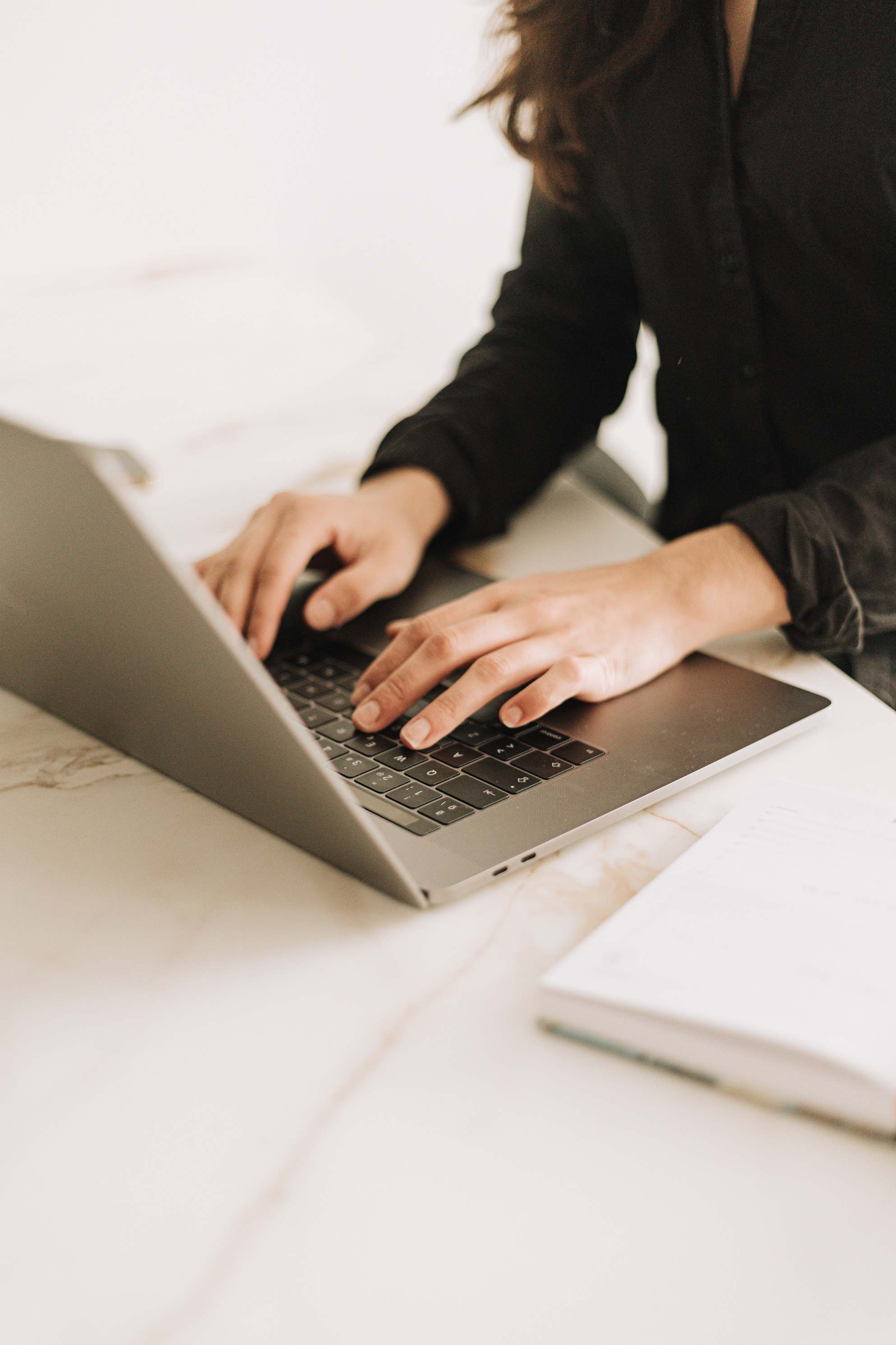 Hands typing on a keyboard at a desk with a monitor in a modern workspace